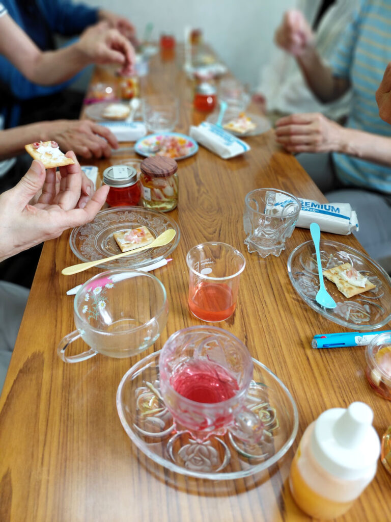 月桃りんご酢に漬けた花びらをクラッカーにのせて試食している様子